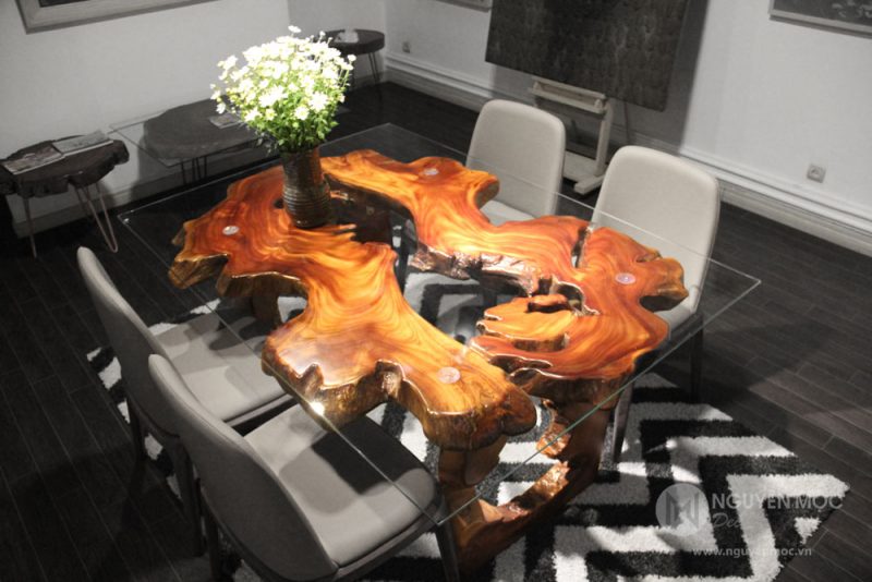 Sử dụng tấm kính trong suốt đặt trên mặt bàn gỗ phù hợp với không gian nội thất hiện đại.