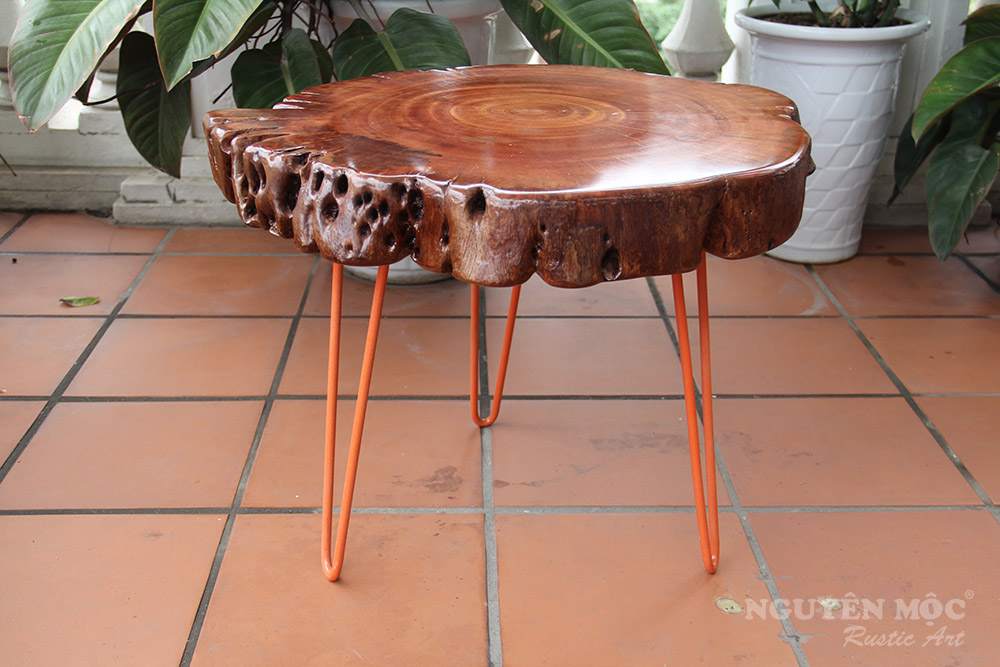 Mặt bàn trà gỗ nguyên thân được thiết kế cùng chân sắt màu cam, mang đến một phong cách Rustic giản dị và mộc mạc trong thiết kế nội thất.